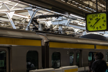 Tokyo, Japan, November 2, 2023: Commuters and Yellow Train at Busy Stationのeditorial素材