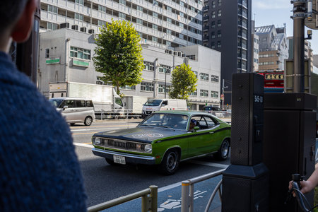 Tokyo, Japan, November 2, 2023: Classic green car driving past modern buildingsのeditorial素材