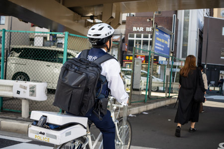 Tokyo, Japan, November 2, 2023: Police Officer on Bicycle Patrolling the Areaのeditorial素材