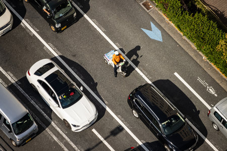 Tokyo, Japan, November 2, 2023: Aerial View of Delivery Worker on Bicycle Amidst Traffic