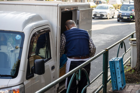 Tokyo, Japan, November 2, 2023: Delivery worker unloading packages from a white vanのeditorial素材