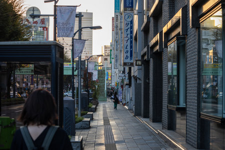 Tokyo, Japan, November 3, 2023: Woman walking on the sidewalk of a quiet Tokyo street in the morning