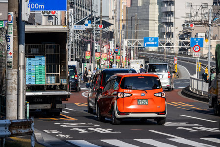 Tokyo, Japan, November 3, 2023: Urban Scene with Delivery Truck and Orange Car in Trafficのeditorial素材