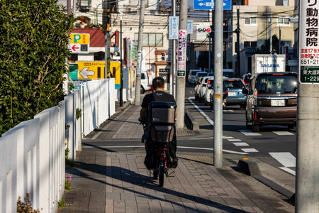 Tokyo, Japan, November 3, 2023: Cyclist on the street with urban backdropのeditorial素材