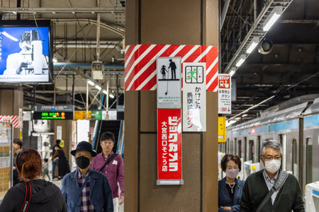 Tokyo, Japan, November 3, 2023: Commuters at a train station with health and safety signsのeditorial素材