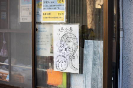 Tokyo, Japan, November 3, 2023: Hand-drawn portrait and notices on restaurant windowのeditorial素材