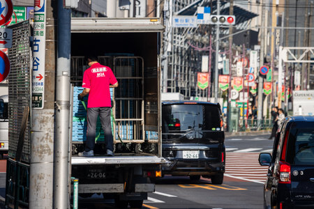 Tokyo, Japan, November 3, 2023: Delivery worker unloading goods from a truck in Tokyo's busy streets