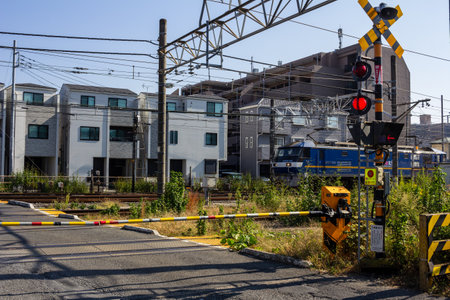 Tokyo, Japan, November 3, 2023: Train crossing with warning lights and barriers in a residential areaのeditorial素材