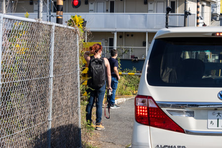 Tokyo, Japan, November 3, 2023: Outdoor photograph of two people leaning against a fence next to a parked carのeditorial素材