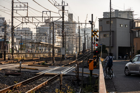 Tokyo, Japan, November 3, 2023: Train tracks and crossing in residential area with cyclist and carsのeditorial素材