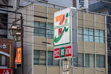 Tokyo, Japan, November 3, 2023: Seven Bank ATM sign with city buildings in the backgroundのeditorial素材