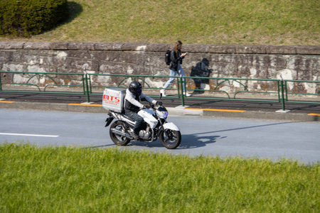 Tokyo, Japan, November 4, 2023: Delivery Rider on Motorcycle with MTS Box in Urban Settingのeditorial素材