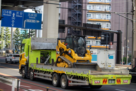 Tokyo, Japan, November 4, 2023: Yellow Skid Steer Loader on Flatbed Truck in Urban Tokyoのeditorial素材