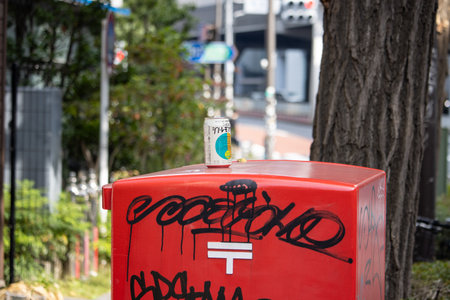 Tokyo, Japan, November 4, 2023: Discarded Beverage Can on Graffiti-Covered Japan Post Mailbox