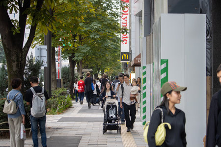Tokyo, Japan, November 4 2023: Urban Street Scene with Pedestrians and Commercial Brand Logos