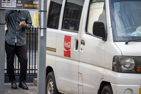 Tokyo, Japan, November 4 2023: Man Walking by a Parked Van with a Coca-Cola Logo