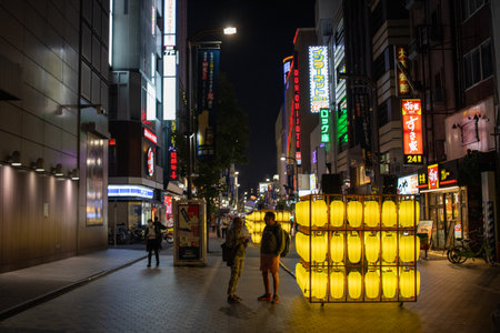 Tokyo, Japan, November 4 2023: Illuminated Yellow Lanterns on Busy Street at Nightのeditorial素材