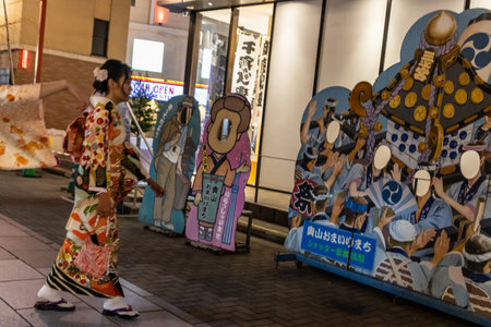 Tokyo, Japan, November 5 2023: Woman in Traditional Kimono Walking Past Cutout Figuresのeditorial素材