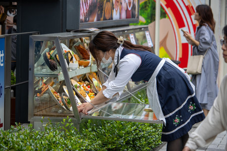 Tokyo, Japan, November 5 2023: Employee Restocking Food Display at Outdoor Stallのeditorial素材
