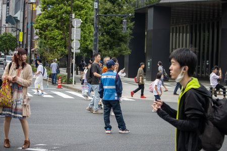 Tokyo, Japan, November 5 2023: Urban Street Scene with Pedestrians and Traffic Control Officerのeditorial素材