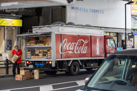 Tokyo, Japan, November 5, 2023: Coca-Cola delivery truck unloading goods in front of a store.のeditorial素材
