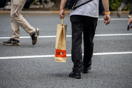 Tokyo, Japan, November 5 2023: Pedestrian with Shopping Bag Crossing Streetのeditorial素材