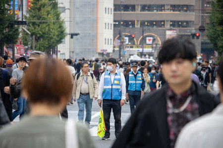 Tokyo, Japan, November 4 2023: Street Scene with Pedestrians and a Crossing Guardのeditorial素材