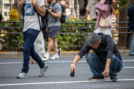 Tokyo, Japan, November 5, 2023: Man setting up camera on city streetのeditorial素材