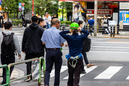 Tokyo, Japan, November 6 2023: Construction Worker Taking Photo in Busy Streetのeditorial素材