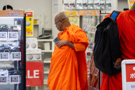 Tokyo, Japan, November 6 2023: Buddhist Monk Using Smartphone in Electronics Storeのeditorial素材