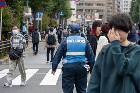 Tokyo, Japan, November 5 2023: City life with pedestrians crossing and security personnelのeditorial素材