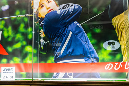 Tokyo, Japan, November 7, 2023: Female golfer in mid-swing on advertisement