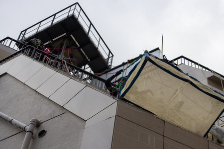 Tokyo, Japan, November 6, 2024: Worker Securing Construction Tarp on Building Roofのeditorial素材