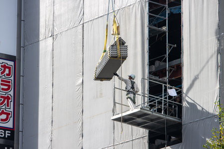 Tokyo, Japan, November 6, 2024: Construction Worker Operating a Crane on Urban Building Siteのeditorial素材