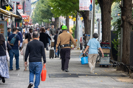 Tokyo, Japan, November 6, 2024: Busy Street Scene with Pedestrians and Security Officerのeditorial素材