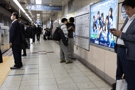 Tokyo, Japan, November 6, 2024: Commuters at Train Station with Advertisement in Backgroundのeditorial素材