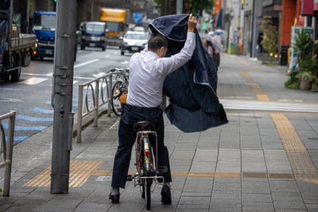 Tokyo, Japan, November 7, 2024: Businessman Covering with Garment in Rainのeditorial素材