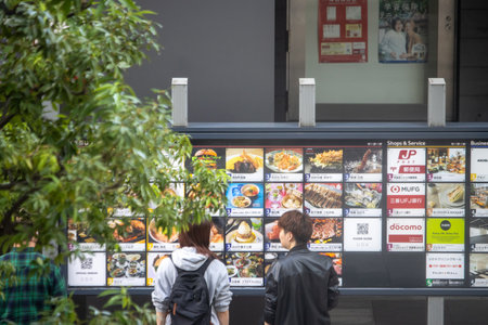 Tokyo, Japan, November 7, 2024: Couple Viewing Restaurant Menu Displayのeditorial素材