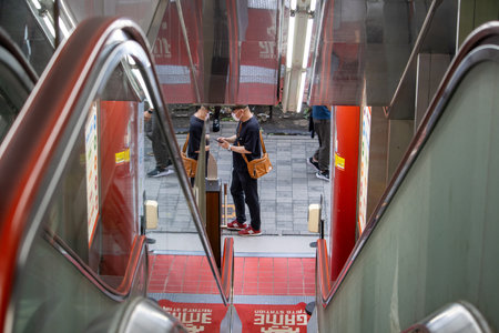 Tokyo, Japan, November 7, 2024: Reflection of Man Using Smartphone on Subway Stairs
