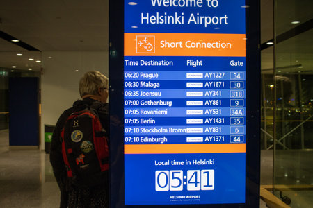 Helsinki, Finland, November 8, 2024: Passenger Viewing Flight Information Board at Airportのeditorial素材