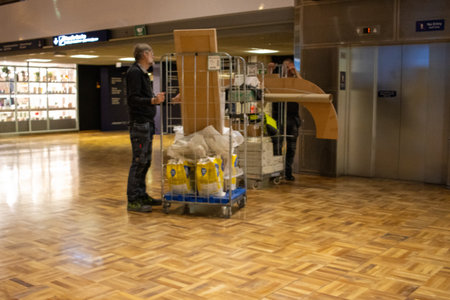 Helsinki, Finland, November 8, 2024: Airport Worker Pushing a Trolley with Goods