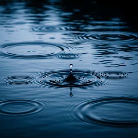 Water drop falling into water with ripples and ripples. Blue background