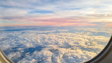 View from the window of an airplane flying over the clouds at sunset
