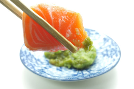 Chopsticks pinch fresh salmon sushi and wasabiの写真素材