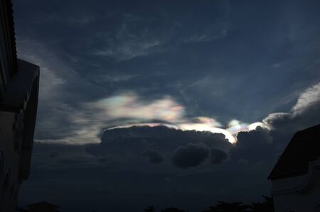 Rainbow beams over clouds on blue sky blackground