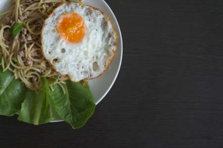 Spaghetti stir fried with Thai Basil spicy sauce with Fried egg  , fusion Thai style , space for textの写真素材