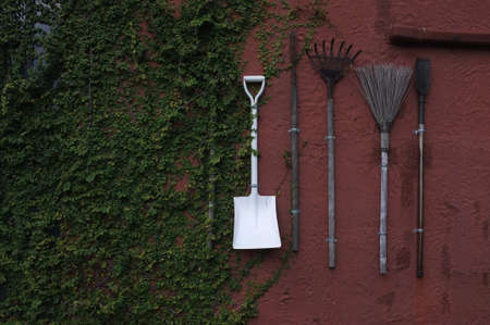 The gardening tools hanging on red cement wall.の写真素材