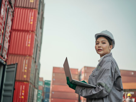 young asian female worker wearing safety helmet and working with container box at shipping yard