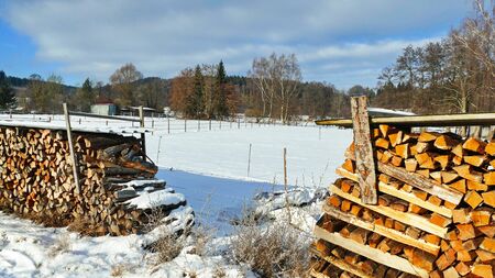 Firewood stacked in winter. Winter landscape with blue skyの写真素材