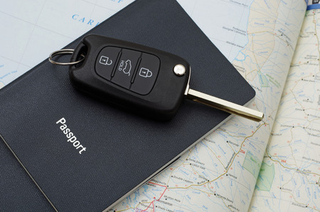 blue passports and black car key on a road mapの写真素材